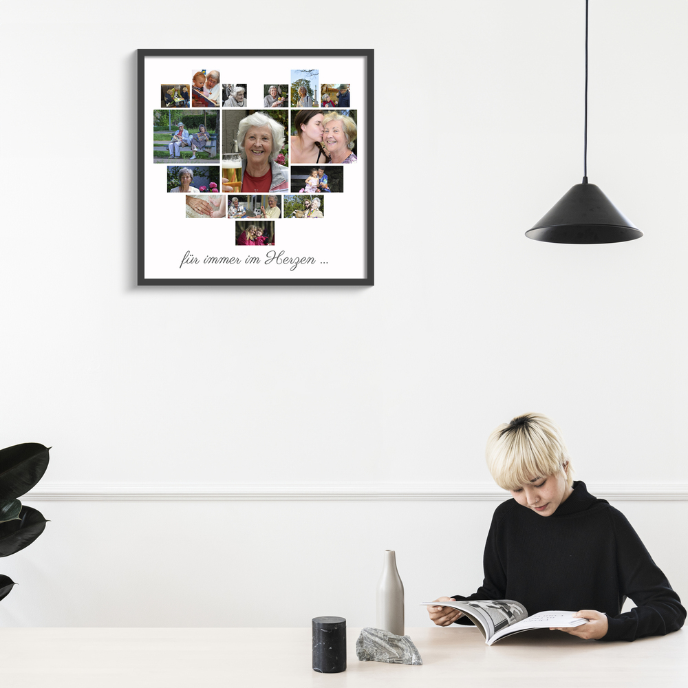 Poster mit Herz-Fotocollage und Gedenkspruch im schwarzen Rahmen an weißer Wand neben einer Pendelleuchte