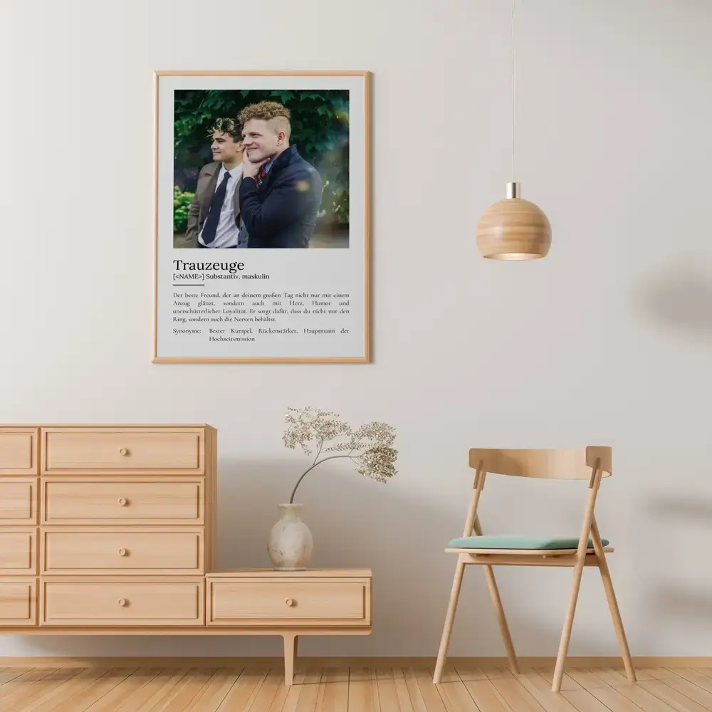 Trauzeugen-Definitionsposter mit Foto im hellen Holzrahmen an der Wand über einer Kommode neben einem Holzstuhl