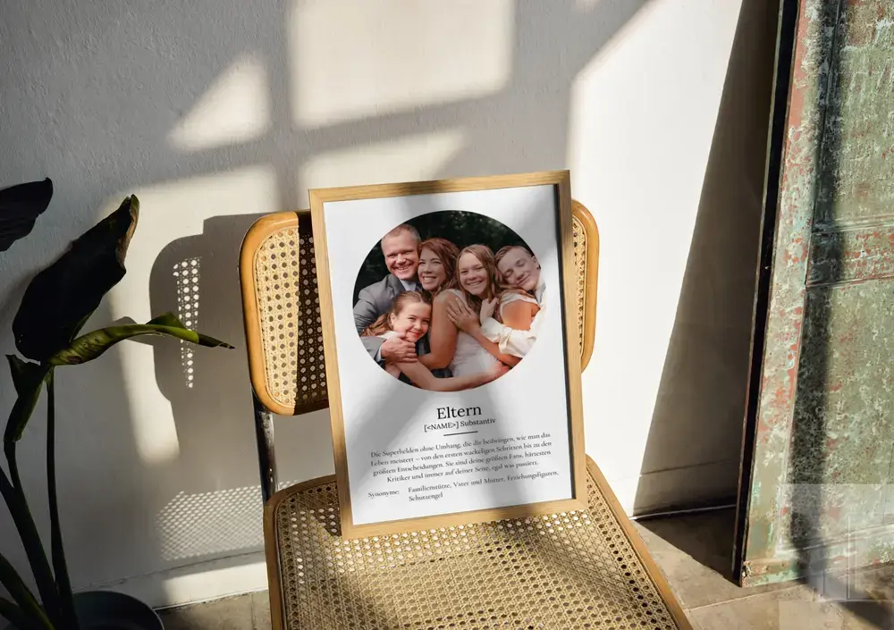 Definitionsposter mit rundem Familienfoto im Holzrahmen auf einem Geflechtstuhl, als Fotogeschenk für Eltern