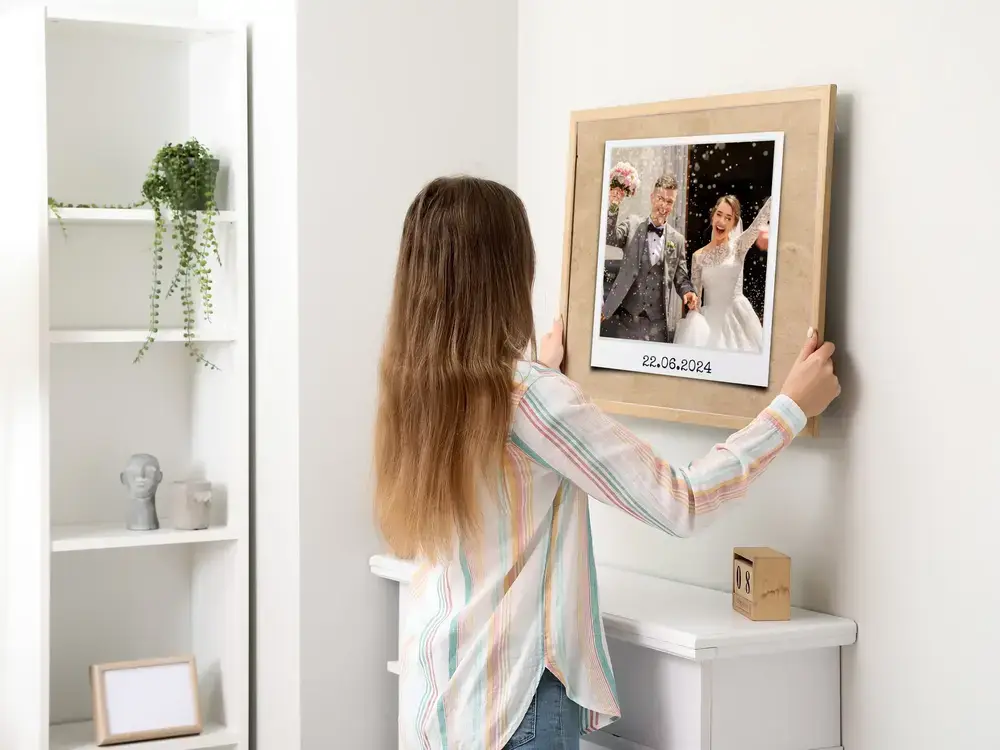 Hochzeitsfoto mit Datum im hellen Holzrahmen an weißer Wand als persönliches Hochzeitsgeschenk
