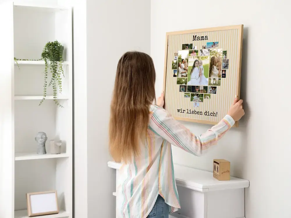 Herzförmige Fotocollage für Mama auf gelb-weiß gestreiftem Hintergrund im hellen Holzrahmen an der Wand