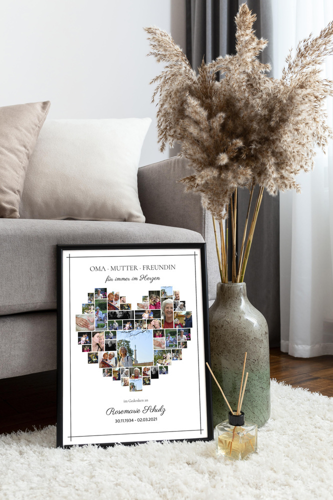 Trauercollage in Herzform im schwarzen Rahmen auf einem hellen Teppich neben Sofa und Vase mit Trockenblumen