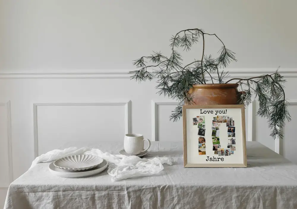 Gerahmte Fotocollage als Zahl 10 mit persönlichem Text auf einem gedeckten Tisch vor einer weißen Wand
